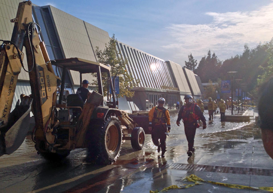 Workers approach Pauley Pavilion, home of UCLA basketball, left, after a 30-inch water main burst on nearby Sunset Boulevard Tuesday, July 29, 2014, in Los Angeles. Water also reached the playing floor of the basketball arena. (AP Photo/Matt Hamilton)