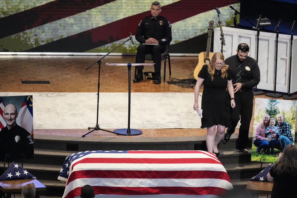 Widow of Officer Joshua Eyer, Ashley, Eyer is escorted to her seat after speaking during a memorial service for Officer Joshua Eyer, Friday, May 3, 2024, in Charlotte, N.C. Police in North Carolina say a shootout that killed Eyer and wounded and killed other officers began as officers approached a home to serve a felony warrant on Monday. (AP Photo/Chris Carlson)