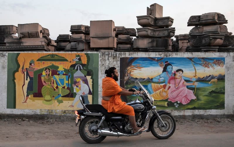 A Hindu priest rides past a workshop where the pillars that Hindu nationalist group Vishva Hindu Parishad (VHP) say will be used to build a Ram temple at the disputed religious site are kept, in Ayodhya