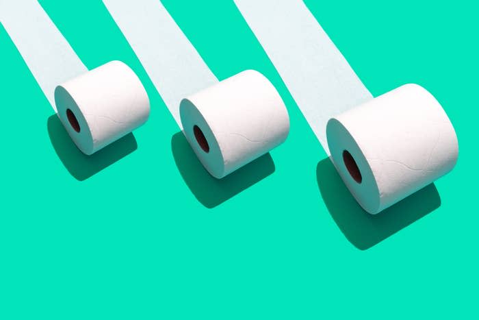 Three rolls of toilet paper casting shadows on a turquoise background, symbolizing hygiene