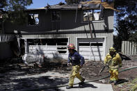 <p>Firefighters Daniel Lizardo, right, and Victor Velasquez walk in front of a fire-ravaged home July 12, 2017, in San Jose, Calif. Relief was arriving after a rough stretch of wildfires all around the U.S. West, with firefighters slowly surrounding once-fierce blazes and evacuees starting to stream back home. (AP Photo/Marcio Jose Sanchez) </p>