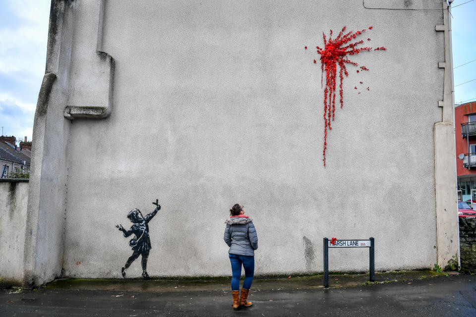 L'ultima creazione dello street artist britannico sulla facciata di un edificio a Bristol, sua città natale in Inghilterra: una bambina con una fionda di fronte a un’esplosione rossa, fatta di petali e fiori di plastica, forse il cuore infranto di Cupido. (Photo by Ben Birchall/PA Images via Getty Images)