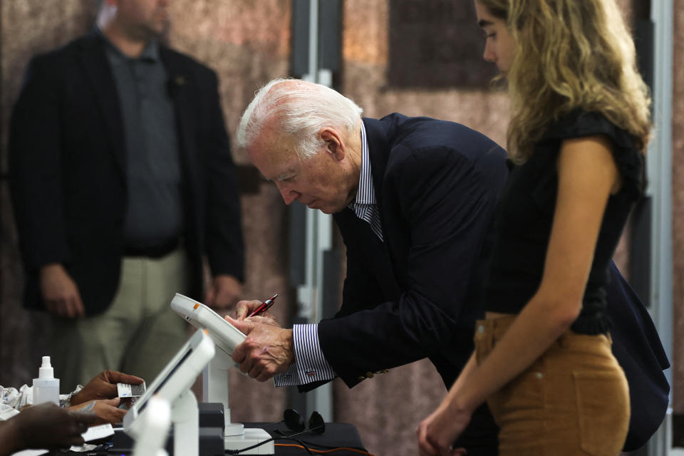 President Biden prepares to cast his vote, with his granddaughter at his side. 