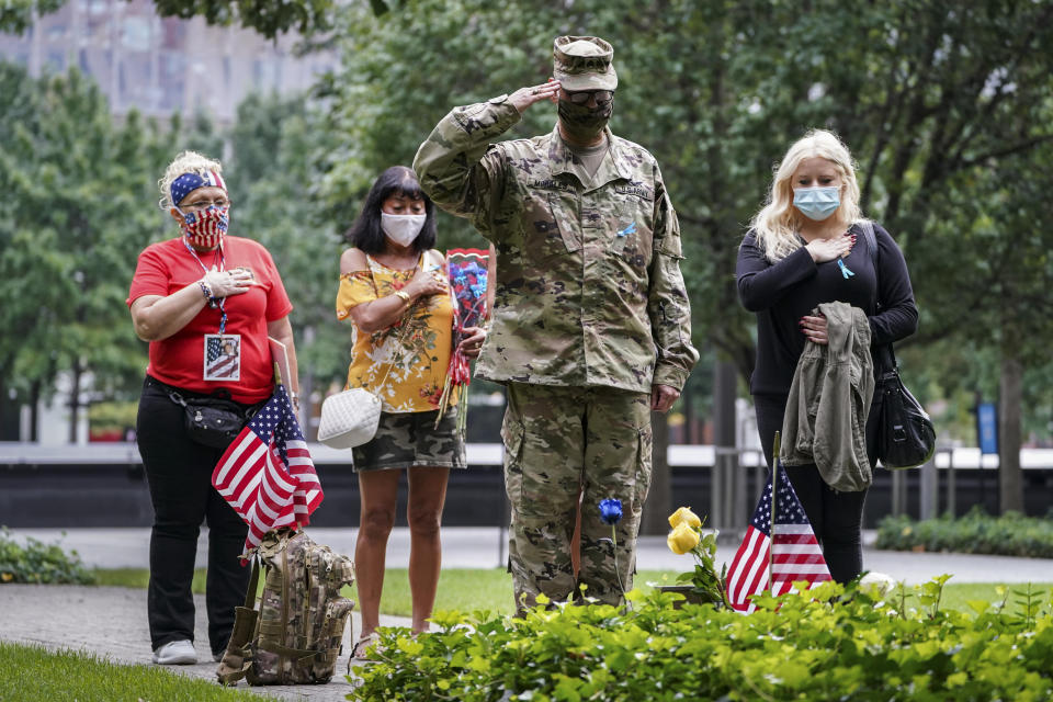 U.S. Army Sgt. Edwin Morales, center right, salutes after placing flowers for fallen FDNY firefighter Ruben D. Correa at the National September 11 Memorial and Museum, Friday, Sept. 11, 2020, in New York. The names of nearly 3,000 victims of the Sept. 11, 2001 terror attacks will be read by family members at a ceremony organized by the Tunnel to Towers Foundation. (AP Photo/John Minchillo)