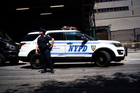 A NYPD officer stands guard after the car reportedly carrying the body of financier Jeffrey Epstein arrived to the medical examiner, after he was found dead in his cell in the Manhattan Correctional Center of New York City, New York