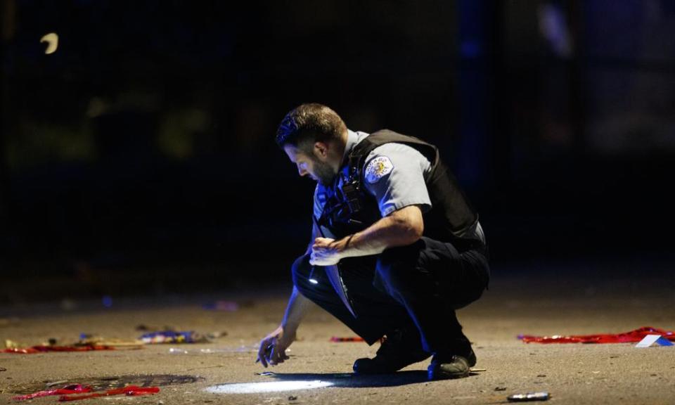 A police officer at the scene of a shooting on Sunday in Chicago , where at least a dozen people were killed in a weekend of violence.