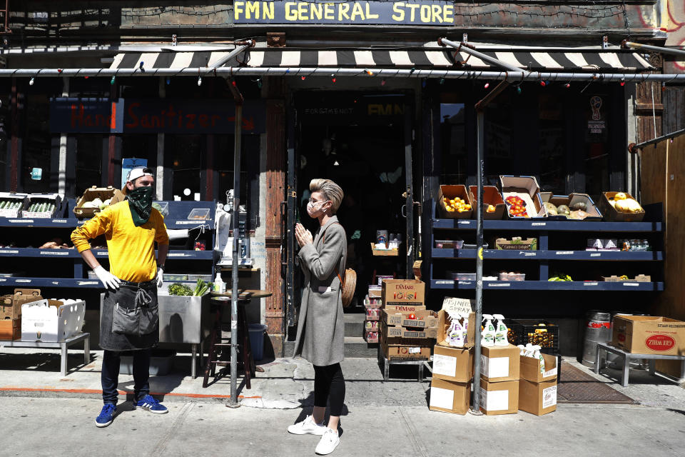 FMN General Store managing partner Derek Tigue, left, talks with neighbor Geraldine Johns in front of the former Forgtmenot bar, which his partners and he converted to a mini-grocery market in March during the current coronavirus outbreak, Wednesday, April 15, 2020, in New York. The owners wanted to keep their loyal customer base happy by meeting people's top needs in the era of COVID-19. (AP Photo/Kathy Willens)