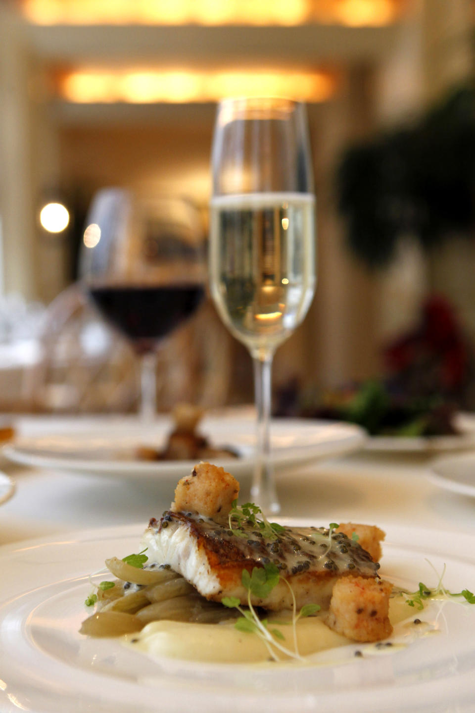 In this Dec. 7, 2012 photo, local snapper with crawfish sausage, creamed potato, fennel, caviar butter, by executive chef Kristin Butterworth, is seen with wine pairings, at the Grill Room of the Windsor Court Hotel in New Orleans. Roughly 50 restaurants in New Orleans are reviving an old Creole custom called reveillon, which stems from the old French tradition of eating a lavish meal after midnight Mass on Christmas Eve. (AP Photo/Gerald Herbert)