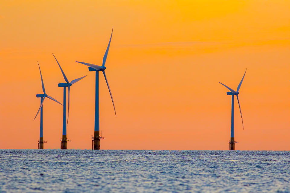 Offshore wind farm energy turbines at dawn. Surreal but natural sunrise at sea. Modernistic image. The future of clean energy production.