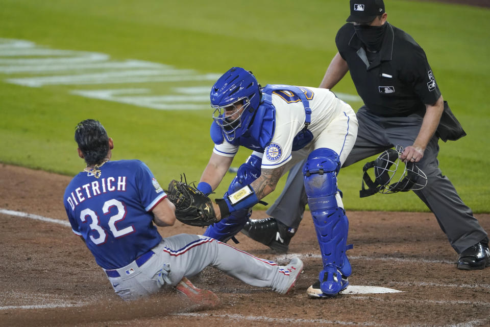 Seattle Mariners catcher Joseph Odom tags out Texas Rangers' Derek Dietrich as home plate umpire Lance Barrett looks on during the seventh inning of a baseball game, Sunday, Sept. 6, 2020, in Seattle. Dietrich was trying to score on a double hit by Leody Taveras. (AP Photo/Ted S. Warren)