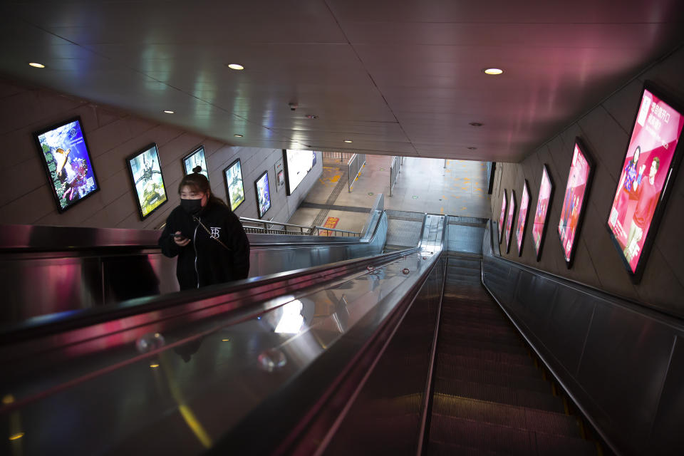 A woman wearing a face mask uses rides an escalator at a nearly empty subway station in Beijing, Wednesday, Jan. 29, 2020. Fears of a virus outbreak have kept many indoors and at home in China's capital. Cultural landmarks such as the Great Wall and Forbidden City have closed their doors to visitors, nearly deserted shopping malls have reduced their operating hours, and restaurants that remain open draw just a handful of customers. (AP Photo/Mark Schiefelbein)