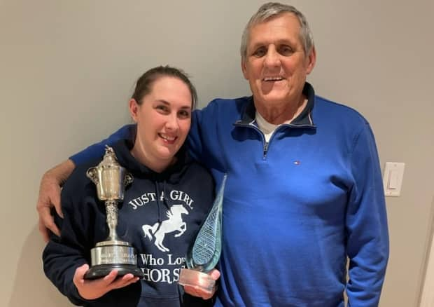 Brown holds Mighty Heart's two trophies from last year with his owner, Lawrence Cordes.