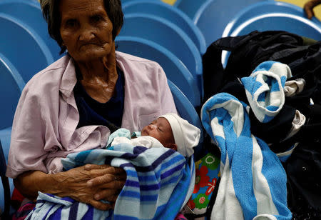 A woman carries a baby at an evacuation centre for victims of Typhoon Haima in San Fernando, la Union in northern Philippines, October 19, 2016. REUTERS/Erik De Castro
