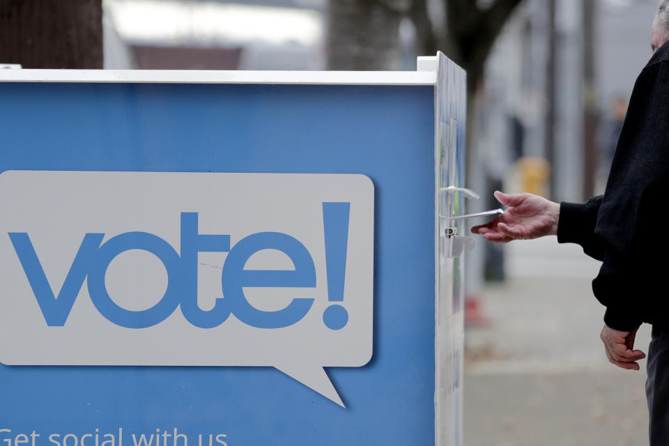 A voter drops a ballot into a ballot drop box Monday, Nov. 4, 2019, in Seattle. Voters in Washington state have a crowded ballot to fill out for this week's election, with a referendum on affirmative action and an initiative on the price of car tabs among the things they are being asked to decide. (AP Photo/Elaine Thompson)