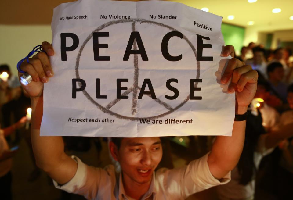 A man holds up a poster during an anti-violence campaign in central Bangkok January 10, 2014. Thailand on Friday played down talk of a military coup ahead of a planned "shutdown" of the capital next week by protesters trying to overthrow Prime Minister Yingluck Shinawatra and said life would go on much as normal. REUTERS/Soe Zeya Tun (THAILAND - Tags: POLITICS CIVIL UNREST)