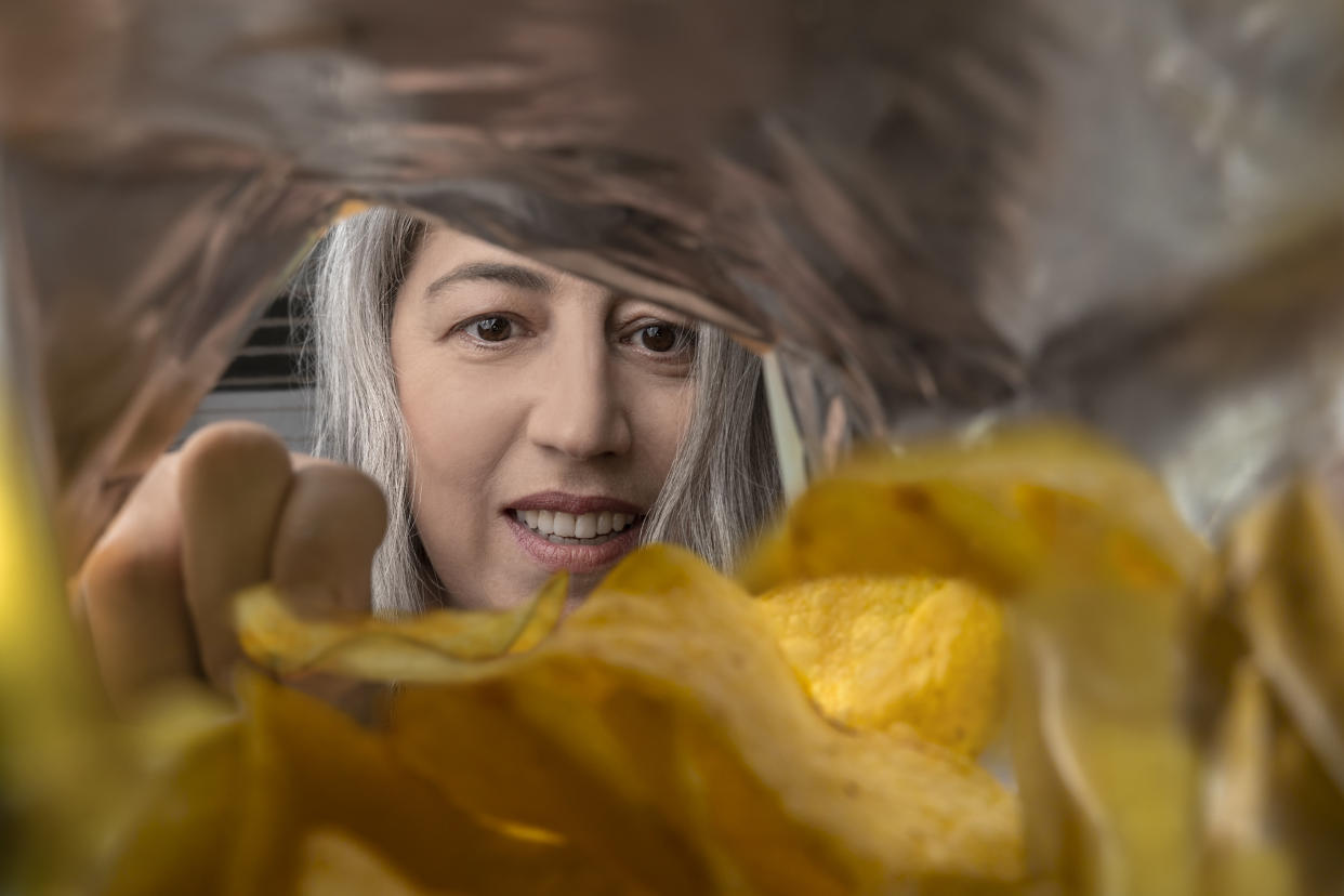 A woman eating chips from a package.