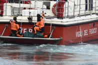 Italian Firefighters scuba divers bring ashore in a green bag the body of one of the victims of the UK flag vessel Bayesian, Wednesday, Aug. 21, 2024. The sail yacht was hit by a violent sudden storm and sunk early Monday, while at anchor off the Sicilian village of Porticello near Palermo, in southern Italy. (AP Photo/Salvatore Cavalli)