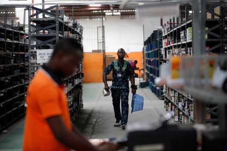 A man walks past shelves with branded packets as he holds a basket at a warehouse for an online store, Jumia in Ikeja district in Nigeria's commercial capital Lagos June 10, 2016. REUTERS/Akintunde Akinleye