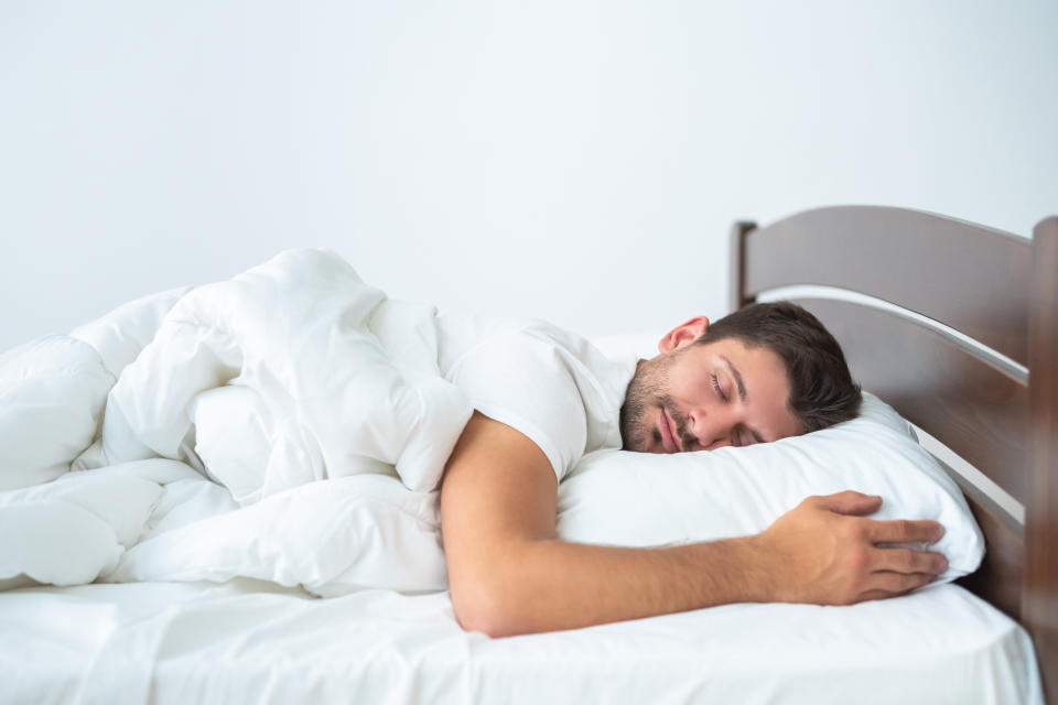 The handsome man sleeping on the bed on the white background