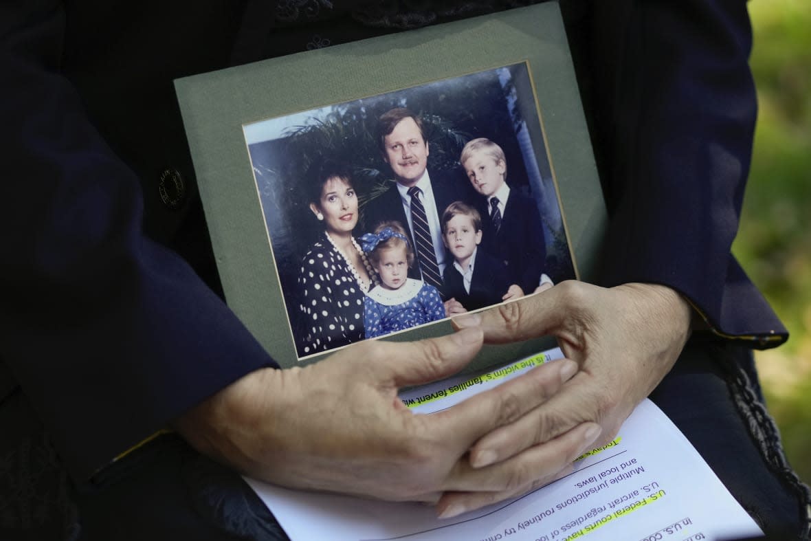 Victoria Cummock, the widow of Pan Am Flight 103 passenger John Cummock who has fought for justice since the 1988 bombing of the flight, holds a contemporaneous portrait of herself, her husband and their then young children, following a press conference Monday, Dec. 12, 2022, in Miami. A Libyan intelligence official accused of making the bomb that brought the plane down over Lockerbie, Scotland, in an international act of terrorism, is to appear Monday in federal court in Washington to face charges. (AP Photo/Rebecca Blackwell)