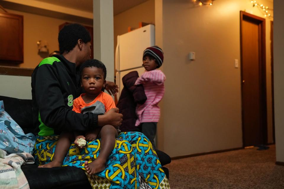 Mariamu Bahome holds her youngest son, Bahome Ilanga while helping her daughter Mawazo Ilanga take off her jacket and school bag in their home in Hickman Loft Apartments on Thursday, Dec. 15, 2022.