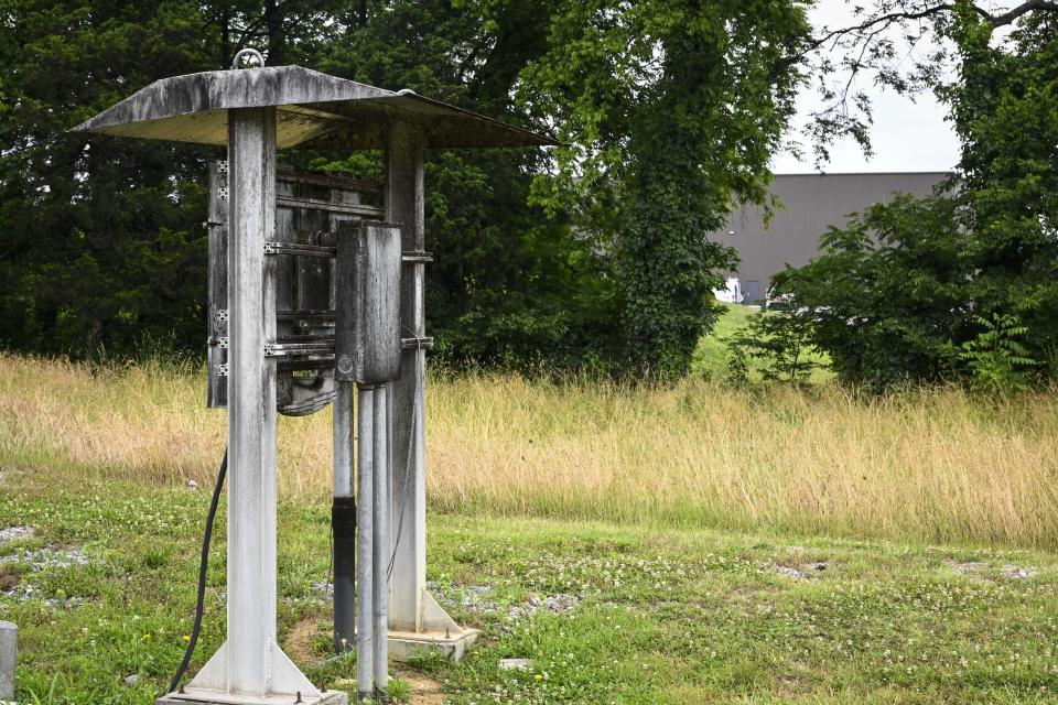 An electrical station is covered with black whiskey fungus, on a property that borders a Jack Daniels barrelhouse complex, partially seen in the background, Wednesday, June 14, 2023, in Mulberry, Tenn. A destructive and unsightly black fungus which feeds on ethanol emitted by whiskey barrels has been found growing on property near the barrelhouses. (AP Photo/John Amis)