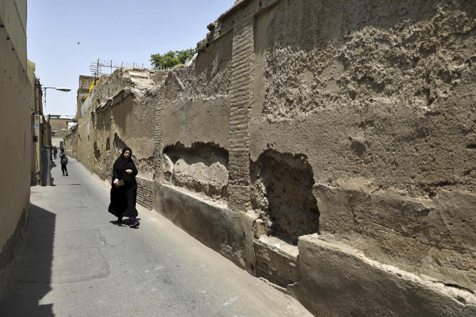 In this July 6, 2019 photo, a woman walks in District 12, a poor area plagued by drug addiction and other social problems, in Tehran, Iran. Iran’s large middle class has been hit hard by the fallout from unprecedented U.S. sanctions, including the collapse of the national currency. Perhaps most devastating has been the doubling of housing prices. The spike has uprooted tenants and made home ownership unattainable for most. (AP Photo/Ebrahim Noroozi)