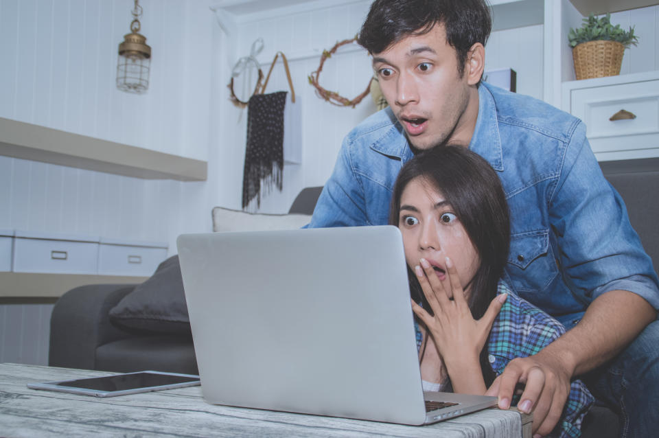 A shocked couple looking at a notebook computer.