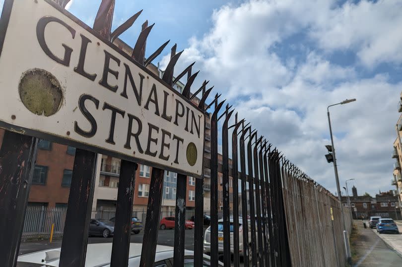 Glenalpin Street sign in Belfast seen here on black fence with carpark in background