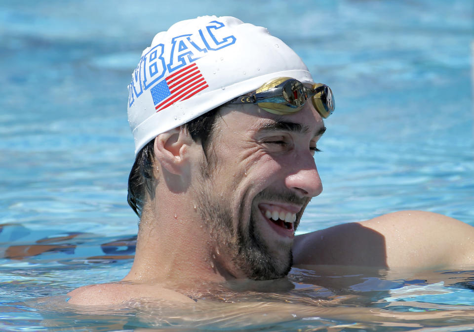 Michael Phelps laughs while talking with coaches during a training session Wednesday, April 23, 2014, in Mesa, Ariz., as he prepares to compete for the first time since retiring after the 2012 London Games. The 22-time Olympic medalist is entered in three events at the Arena Grand Prix starting Thursday. (AP Photo/Matt York)