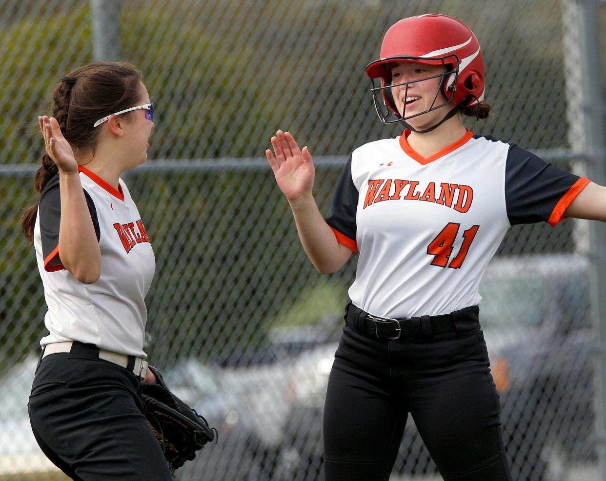 Wayland’s Sofia Simmons (41) gets congratulations from teammate Maya Lee (left) after crossing the plate during its softball game with Dover-Sherborn in Dover.