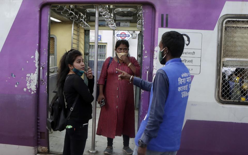 A municipal worker gives a commuter a penalty for not using a face mask at Chhatrapati Shivaji Maharaj Terminus in Mumbai, India, Saturday, Feb. 20, 2021. Health officials have detected a spike in COVID-19 cases in several pockets of Maharashtra state, including in Mumbai, the country's financial capital. (AP Photo/Rajanish Kakade)