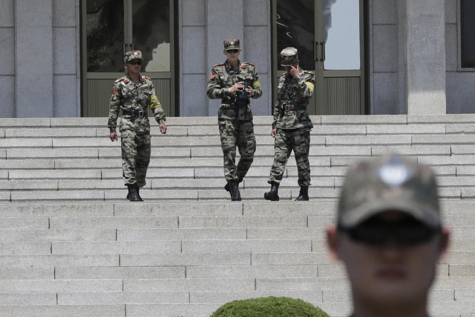 In this June 12, 2019, photo, North Korean soldiers look at the South side as a South Korean soldier, foreground right, stands during a press tour at the border village of Panmunjom in the Demilitarized Zone, South Korea. South Korea says two of four North Korean fishermen who were rescued off a boat drifting in South Korean waters will remain in the country after expressing their desire to defect. Seoul's Unification Ministry on Tuesday, June 18, 2019 said the two other fishermen were sent back to North Korea through the inter-Korean village. (AP Photo/Lee Jin-man)