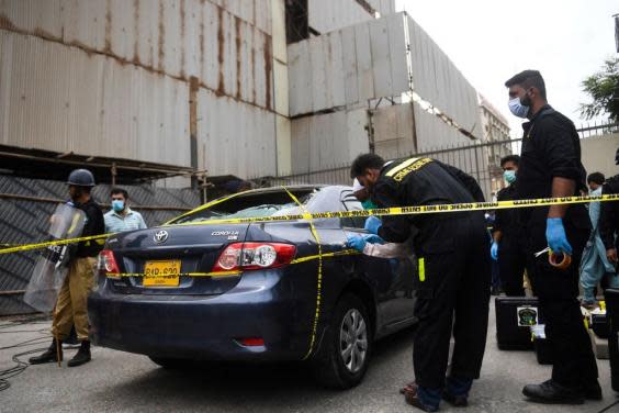 Members of Crime Scene Unit investigate a car used by alleged gunmen at entrance of Stock Exchange building (Getty Images)