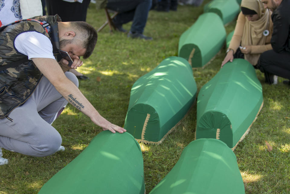 Mourners pray next to coffins in Potocari near Srebrenica, Bosnia, Thursday, July 11, 2019. The remains of 33 victims of the Srebrenica massacre will be buried 24 years after Serb troops overran the eastern Bosnian Muslim enclave of Srebrenica and executed some 8,000 Muslim men and boys, which international courts have labeled as an act of genocide. (AP Photo/Darko Bandic)