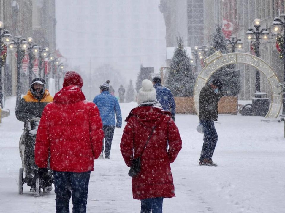 People walk along Sparks Street as it snows in downtown Ottawa on Saturday, Dec. 4, 2021. On Saturday, the city's health officials reported 63 new cases of COVID-19.  (Joseph Tunney/CBC - image credit)