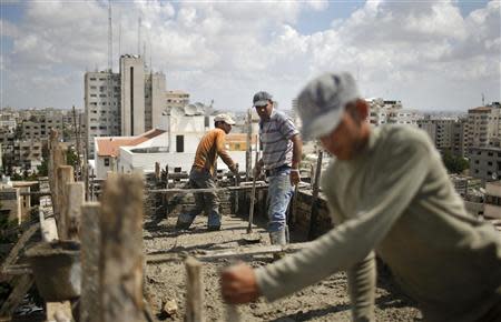 Palestinian workers flatten cement on the roof of a building under construction in Gaza City September 22, 2013. REUTERS/Mohammed Salem