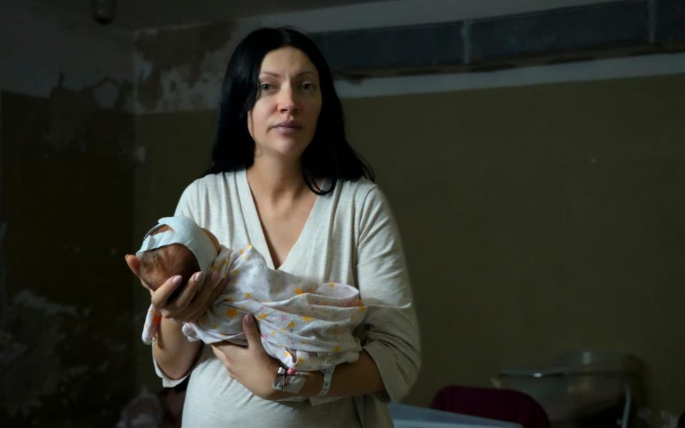  A woman holds her newborn girl in the basement of a maternity hospital converted into a bomb shelter in Kyiv - Efrem Lukatsky /AP