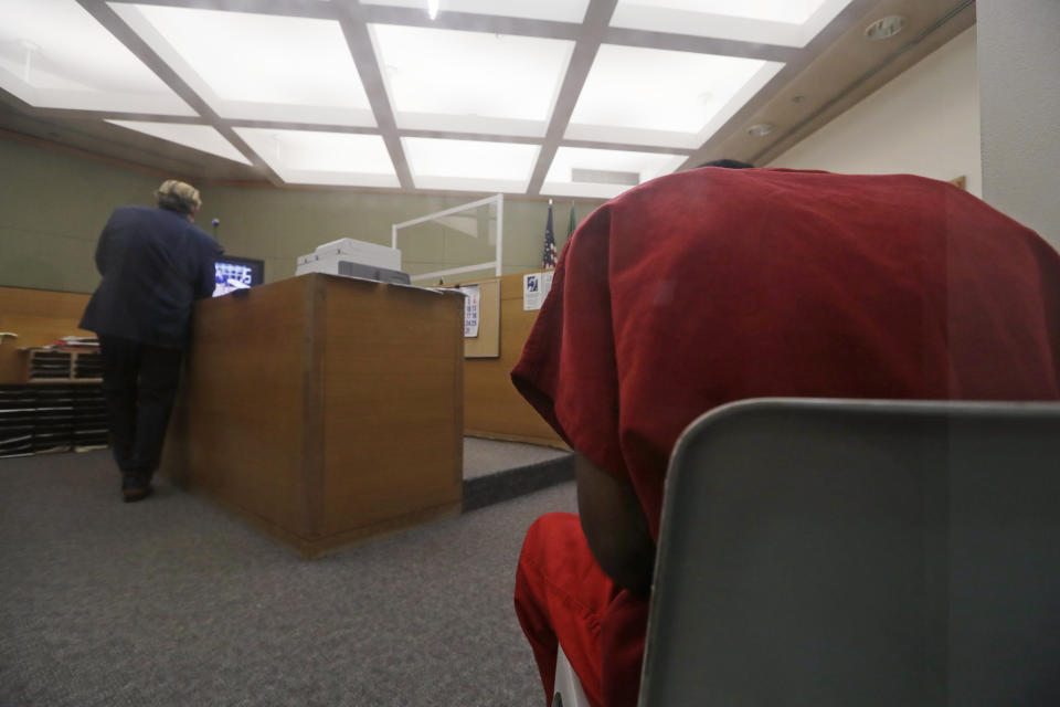 Attorney John Henry Browne, left, stands in view of a video feed as his client Dawit Kelete sits in a chair, right, during a court appearance Monday, July 6, 2020, in Seattle. Kelete is accused of driving a car onto a closed Seattle freeway and hitting two protesters, killing one, over the weekend. Seattle has been the site of prolonged unrest over the death of George Floyd, a Black man who was in police custody in Minneapolis. (AP Photo/Elaine Thompson)