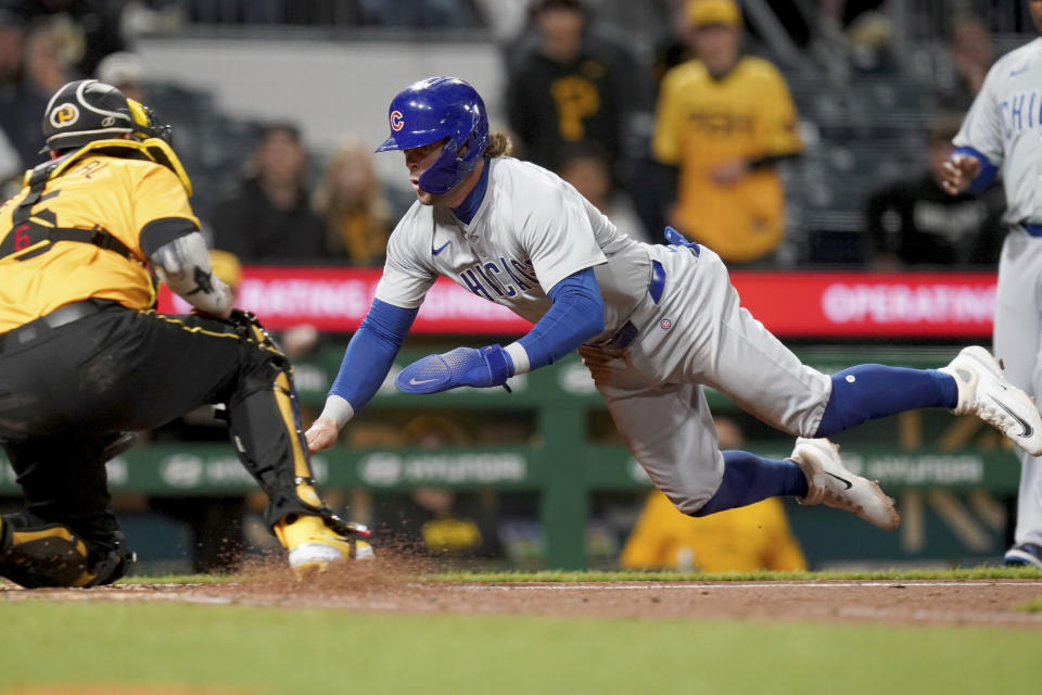 Chicago Cubs' Nico Hoerner, front right, slides into home plate to score against Pittsburgh Pirates catcher Yasmani Grandal , left,during the fifth inning of a baseball game Friday, May 10, 2024, in Pittsburgh. (AP Photo/Matt Freed)
