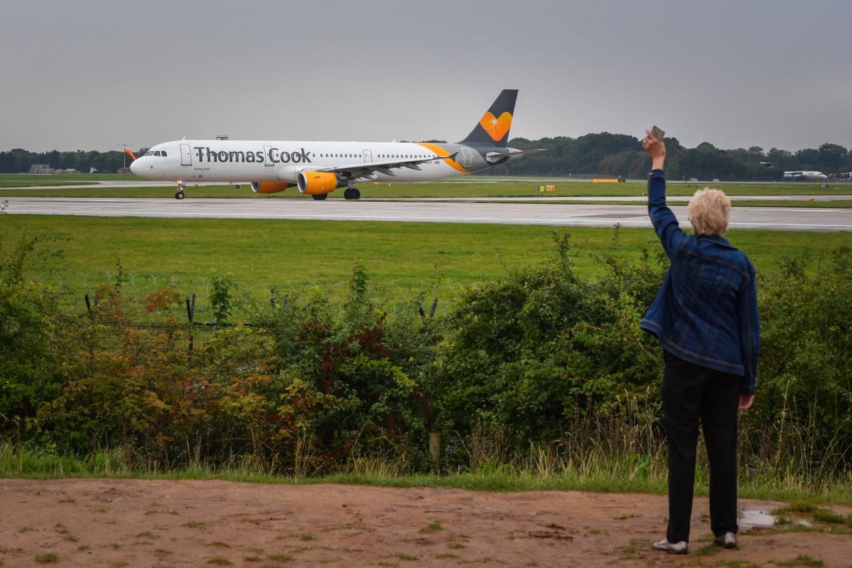 A woman waves as a Thomas Cook aircraft departs from Terminal 1 at Manchester Airport: Getty Images