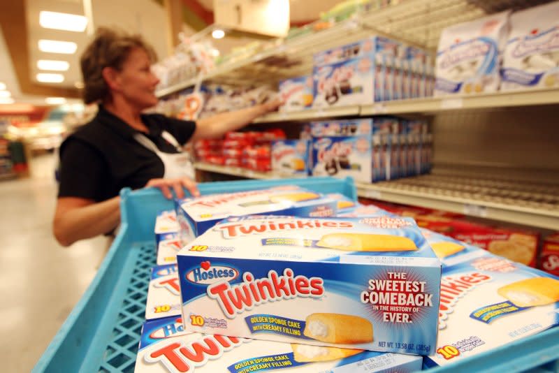 A bakery manager stocks shelves at a Schnucks grocery store in Ballwin, Mo., with Hostess Twinkies and CupCakes (2013). Hostess Brands was acquired by J.M. Smucker Co. on Monday for $5.6 billion. File Photo by Bill Greenblatt/UPI