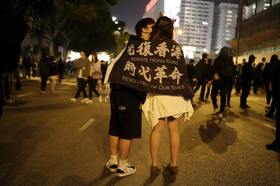 A couple kiss draped in a banner with the words "Liberate Hong Kong, Revolution of our Times" during a rally on Christmas Eve in Hong Kong on Tuesday, Dec. 24, 2019. More than six months of protests have beset the city with frequent confrontations between protesters and police. (AP Photo/Kin Cheung)