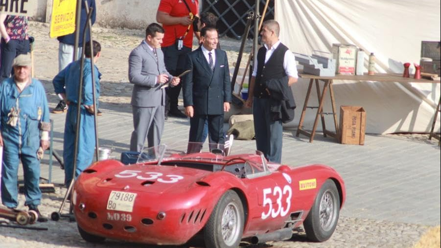 a group of people standing around a red race car