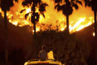 <p>King Bass, 6, left, sits and watches the Holy Fire burn from on top of his parents’ car as his sister Princess, 5, rests her head on his shoulder Thursday night, Aug. 9, 2018 in Lake Elsinore, Calif. (Photo: Patrick Record/AP) </p>