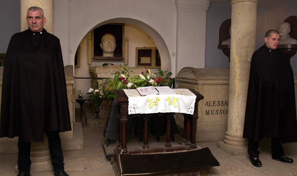 FILE - Maurizio Villata, left, and Beppe (last name not available) members of the "Associazione Guardia D'onore Benito Mussolini" (Benito Mussolini Honor Guard Association) stand by the tomb of fascist dictator Benito Mussolini in the family crypt in his native town of Predappio, central Italy, in this Feb. 8, 2002 file photo. Italy's failure to come to terms with its fascist past is more evident as it marks the 100th anniversary, Friday, Oct. 28, 2022, of the March on Rome that brought totalitarian dictator Benito Mussolini to power as the first postwar government led by a neo-fascist party takes office. (AP Photo/Venanzio Raggi, File)