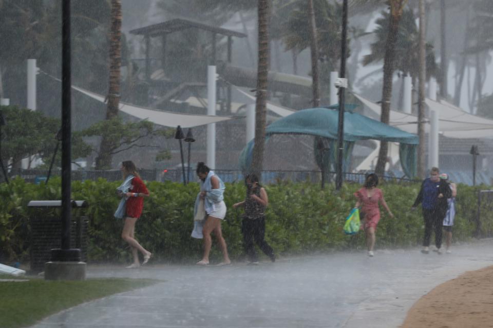 People scramble to get out of the heavy rain on Waikiki Beach, Monday, Dec. 6, 2021, in Honolulu. 