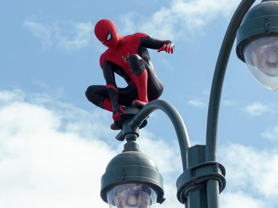 Tom Holland perched on a lamp post as Spider-Man in "Spider-Man: No Way Home."