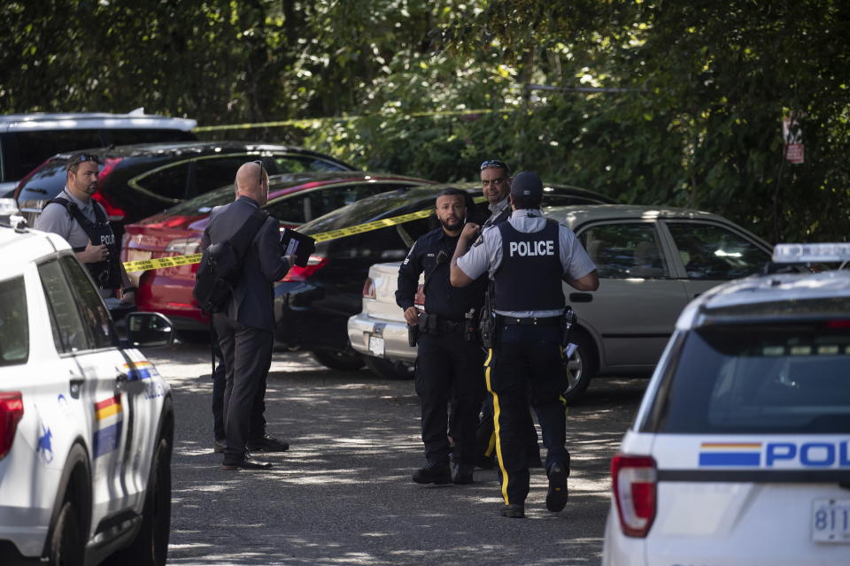 RCMP and Surrey Police officers work at the scene of a shooting near a red Tesla vehicle, back, in Surrey, British Columbia, Canada, on Thursday, July 14, 2022. Ripudaman Singh Malik, the man acquitted in the 1985 Air India terrorist bombing, appears to have been killed in the shooting, according to several media outlets. (Darryl Dyck/The Canadian Press via AP)