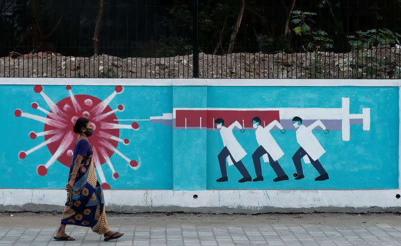 Woman walks past a graffiti amidst the spread of the coronavirus disease, in Mumbai